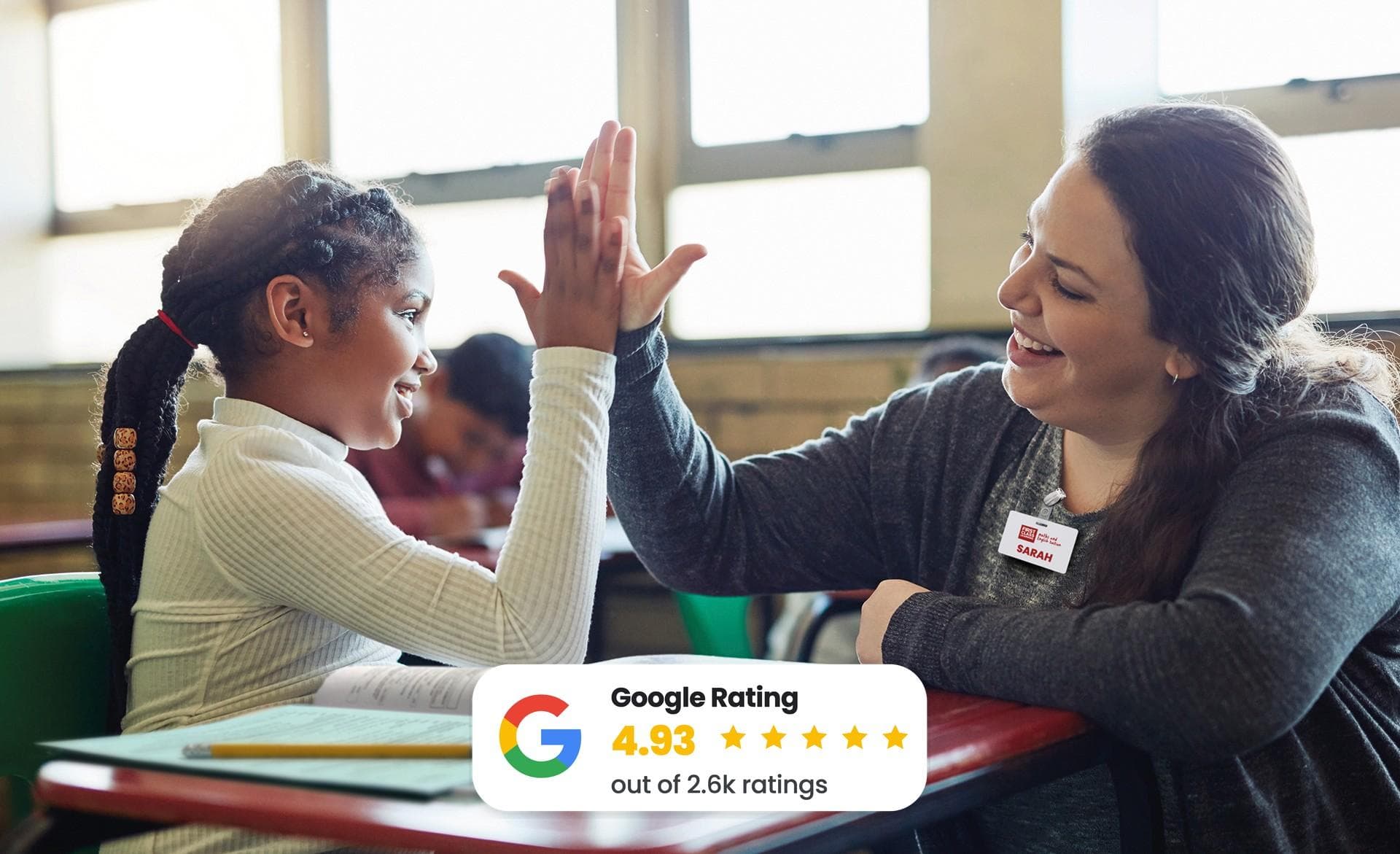 A teacher and student high-five joyfully in a classroom. A Google rating of 4.93 out of 5 stars is displayed.